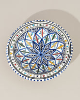 A ceramic decorative plate with a hand-painted geometric pattern predominantly in blue and white colors.